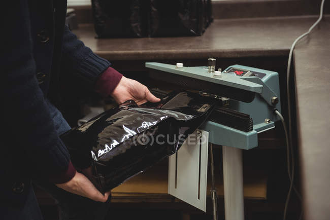 A meio da seção do homem que embala o saco de café da máquina de selagem no café — Fotografia de Stock