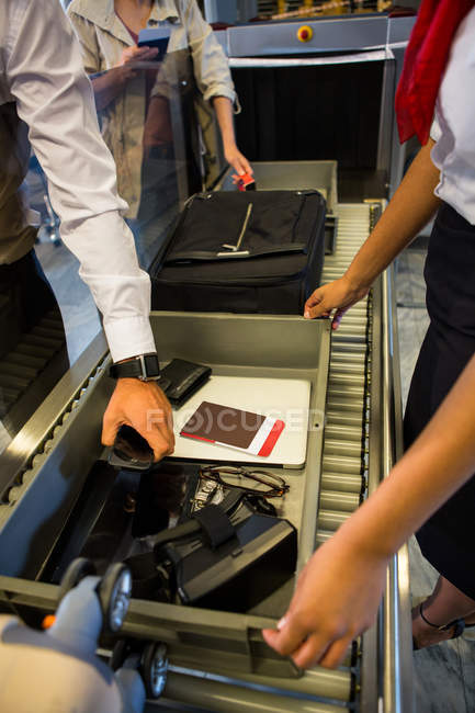 Бізнесмен кладе речі в лоток для перевірки безпеки в терміналі аеропорту — стокове фото