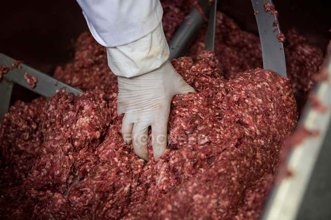 Nahaufnahme eines Metzgers, der Hackfleisch aus der Maschine entfernt — Stockfoto
