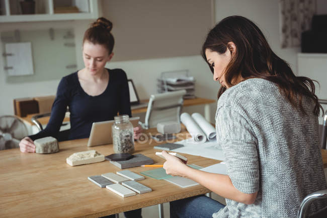 Business executive looking at stone slab while colleague using digital tablet in office — Stock Photo