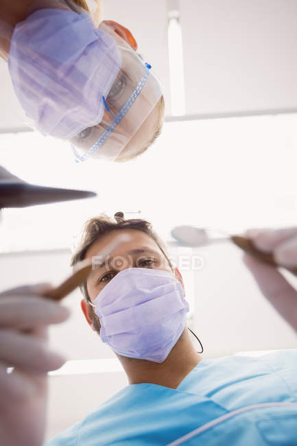 Visão de baixo ângulo de dentistas segurando ferramentas odontológicas na clínica odontológica — Fotografia de Stock