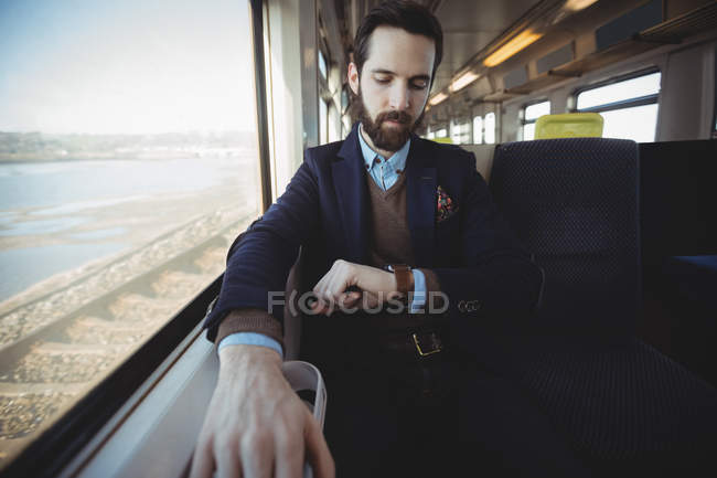 Бізнесмен перевіряє час на смарт-годиннику під час подорожі в поїзді — стокове фото