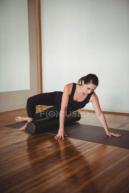 Mid adult woman exercising with foam roll in fitness studio — Stock Photo