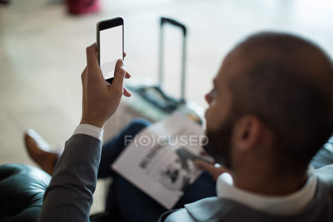 Бізнесмен використовує мобільний телефон у зоні очікування в терміналі аеропорту — стокове фото