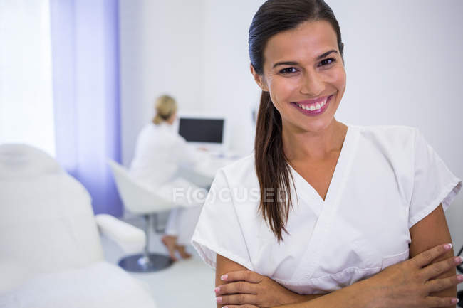 Портрет усміхненого стоматолога, що стоїть з обіймами, схрещеними у клініці — стокове фото