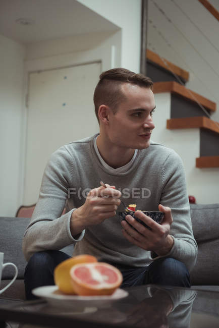 Young adult man looking away while having breakfast at home — Stock Photo