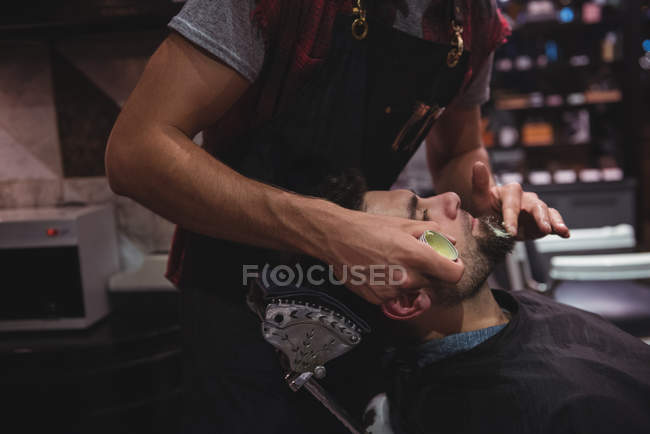 Mittelteil des Friseurs Creme auf Client-Bart im Friseurladen — Stockfoto
