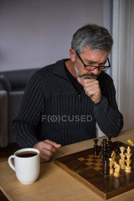 Hombre atento jugando ajedrez en casa - foto de stock