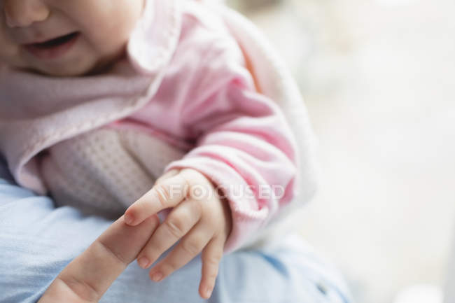 Close-up of cute baby holding mother finger at home — Stock Photo