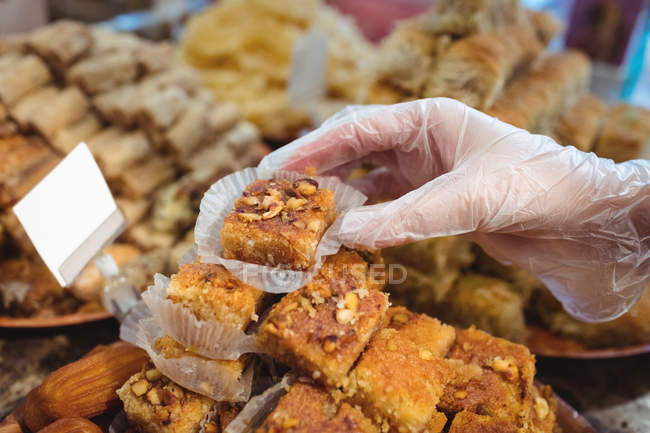 Close-up of female shopkeeper arranging turkish sweets at counter in shop — Stock Photo