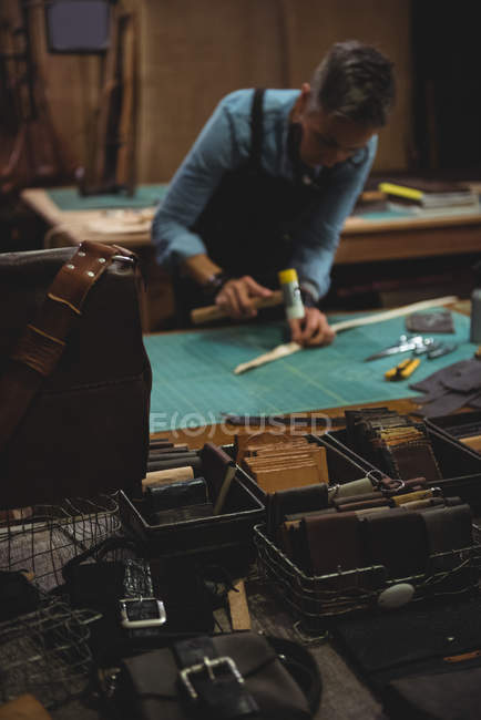 Зрелая ремесленница молотит кожей в мастерской — стоковое фото