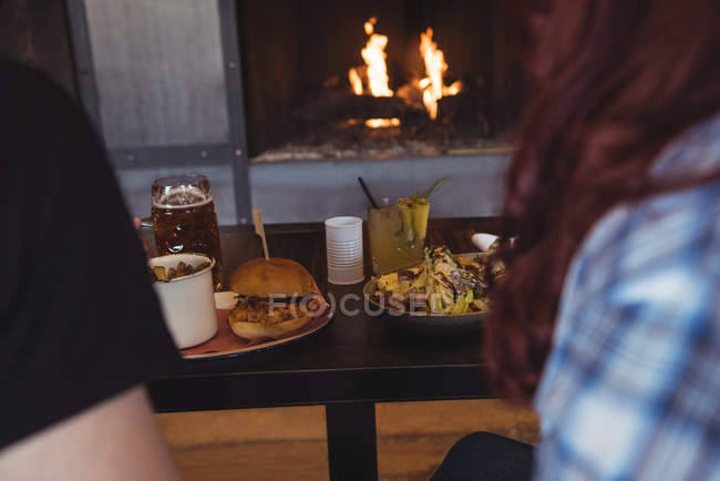 Gros plan du couple assis au comptoir du bar avec de la nourriture — Photo de stock