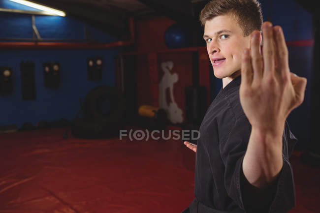 Jeune joueur de karaté adulte effectuant position de karaté dans un studio de fitness — Photo de stock