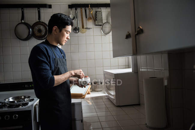Man using pestle and mortar in kitchen at home — Stock Photo