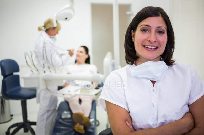 Retrato de una doctora de pie con los brazos cruzados en la clínica - foto de stock