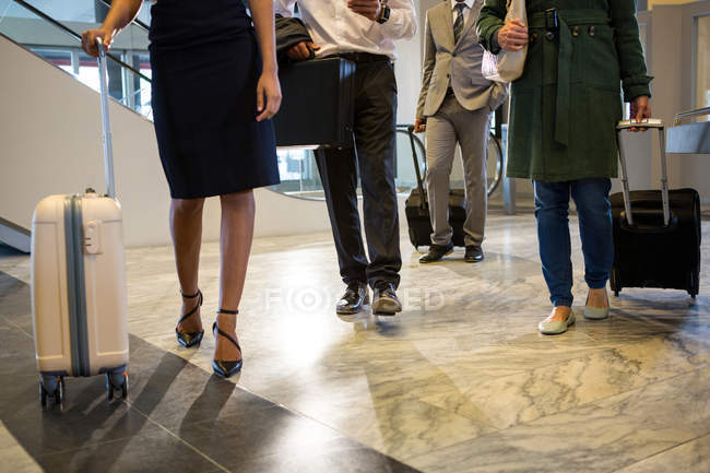 Mid-section of passengers walking at airport terminal with luggage — Stock Photo