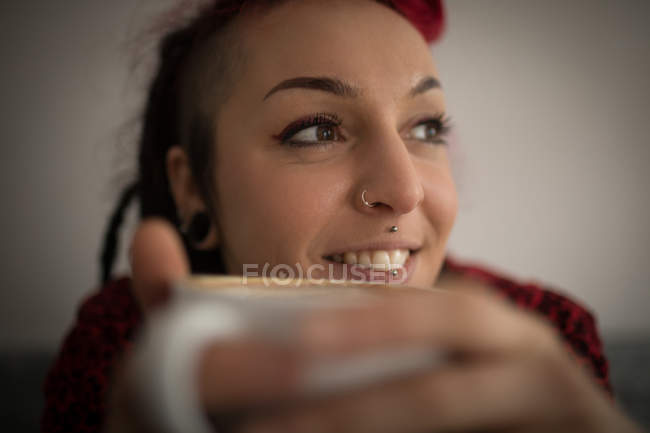 Mujer sonriente tomando café en la cafetería - foto de stock