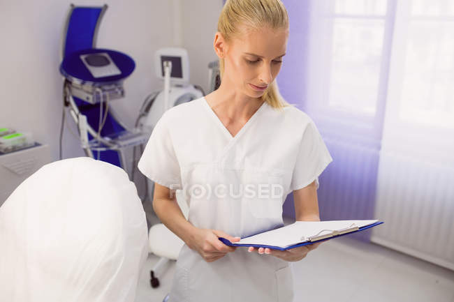 Female doctor checking medical report at clinic — Stock Photo
