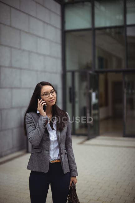 Бізнес-леді розмовляє на мобільному телефоні поза офісною будівлею — стокове фото