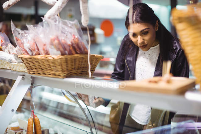 Frau sucht verpackte Lebensmittel an Lebensmitteltheke im Supermarkt aus — Stockfoto