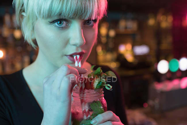 Retrato de una hermosa mujer tomando un cóctel en el bar - foto de stock