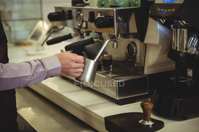 Средняя секция человека, готовящего кофе в кафе — стоковое фото
