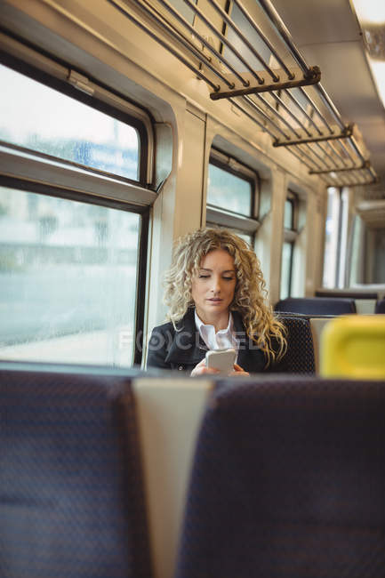 Mulher de negócios adulta média usando smartphone enquanto viaja — Fotografia de Stock