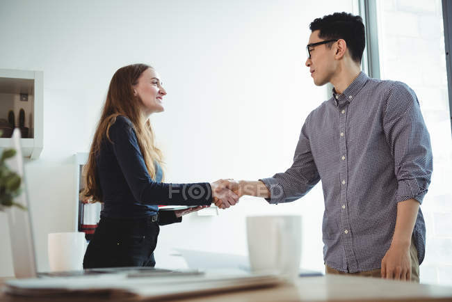 Ejecutivos de negocios estrechándose la mano en la oficina - foto de stock