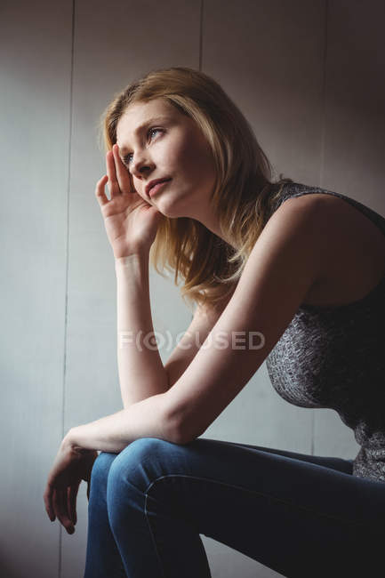 Продумана жінка сидить з рукою на лобі вдома — стокове фото
