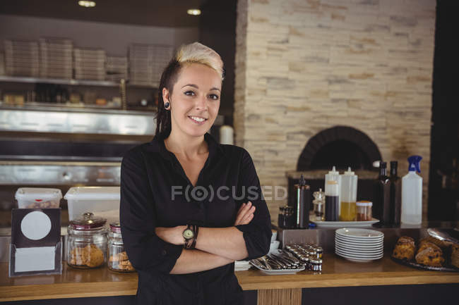 Donna in piedi con le braccia incrociate in cucina al caffè — Foto stock