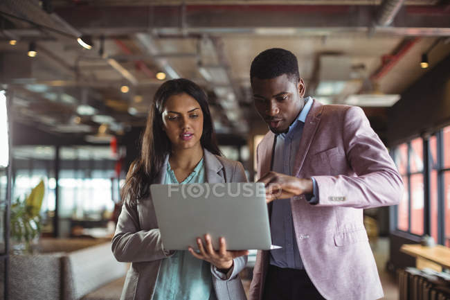 Бизнесмен и коллега обсуждают за ноутбуком в офисе — стоковое фото