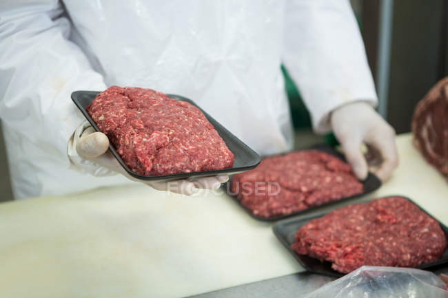 Close-up de açougueiro segurando carne picada crua em bandejas — Fotografia de Stock