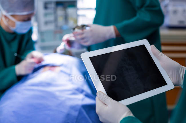 Surgeon using digital tablet while operating patient in operation theater of hospital — Stock Photo