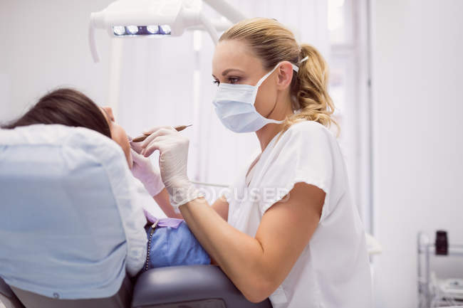 Dentist examining female patient in clinic — Stock Photo