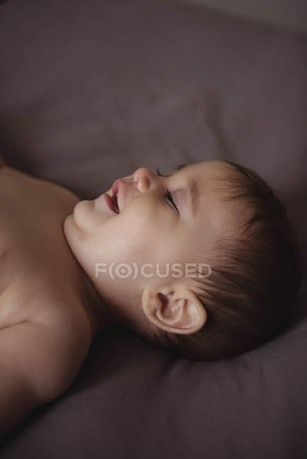 Cute baby lying on bed in bedroom at home — Stock Photo