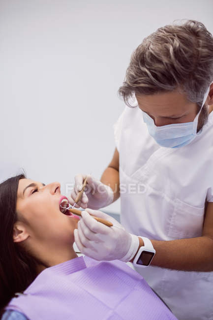 Dentista examinando dientes de paciente femeninos en clínica - foto de stock
