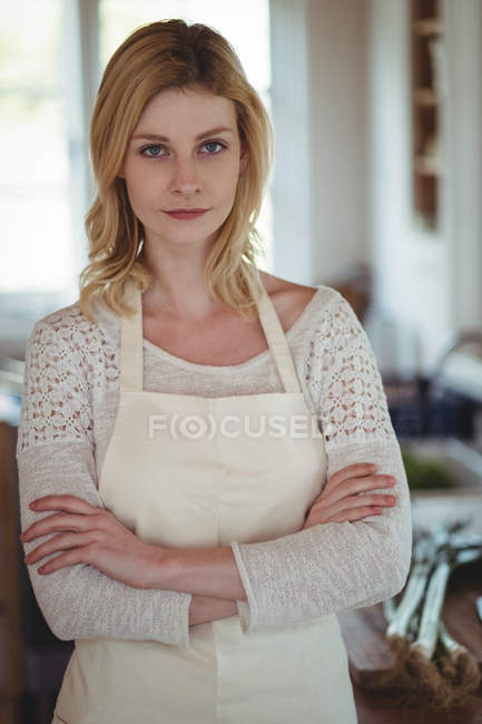 Retrato de mulher bonita de pé com os braços cruzados na cozinha — Fotografia de Stock