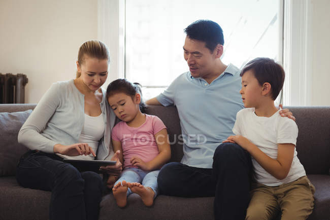 Улыбающиеся родители и дети с помощью цифрового планшета в гостиной — стоковое фото