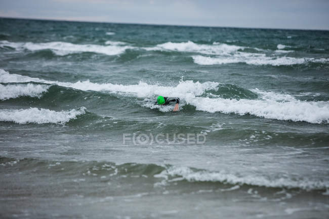 Sportler im Neoprenanzug schwimmt im Meer — Stockfoto