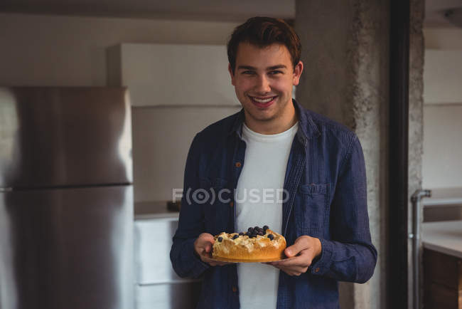 Веселый мужчина держит черничный торт в гостиной дома — стоковое фото