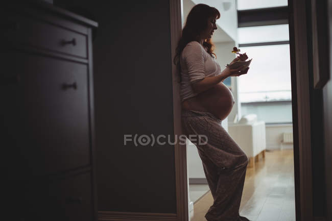 Беременная женщина ест салат дома — стоковое фото