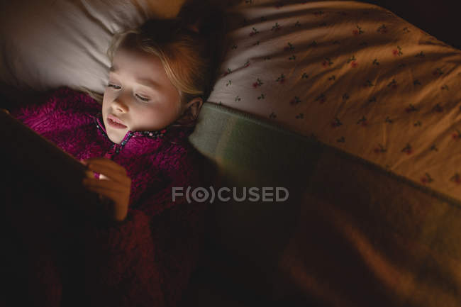 Девушка с помощью цифрового планшета во время отдыха в спальне дома — стоковое фото