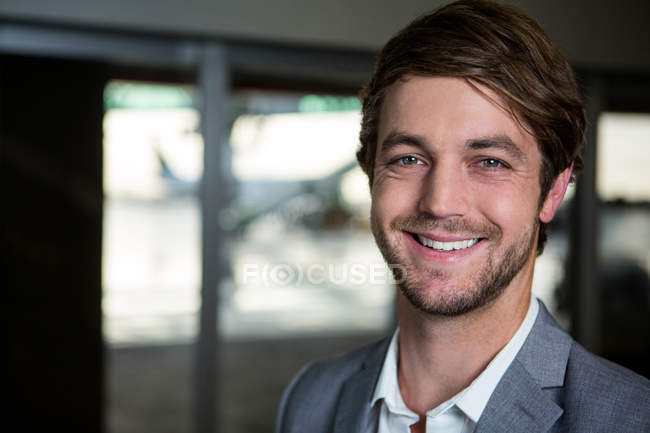Portrait of a smiling businessman standing at airport terminal — Stock Photo