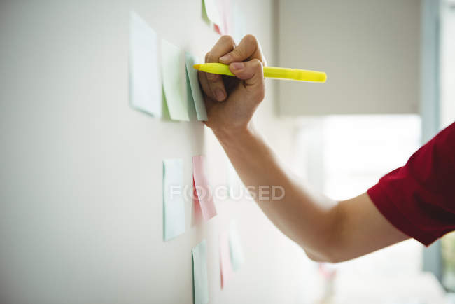 Exécutif d'entreprise écrivant sur des notes collantes au bureau — Photo de stock
