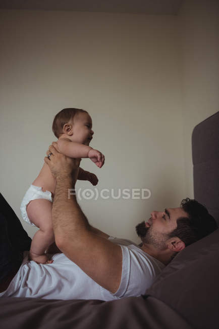 Padre jugando con el niño en el dormitorio en casa - foto de stock