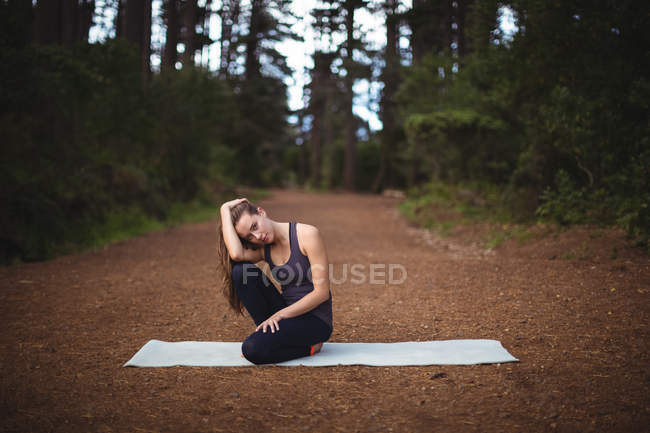 Porträt einer Frau, die im Wald auf einer Gymnastikmatte sitzt — Stockfoto