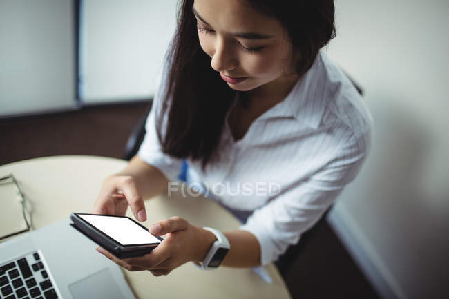 Empresária usando telefone celular no escritório — Fotografia de Stock