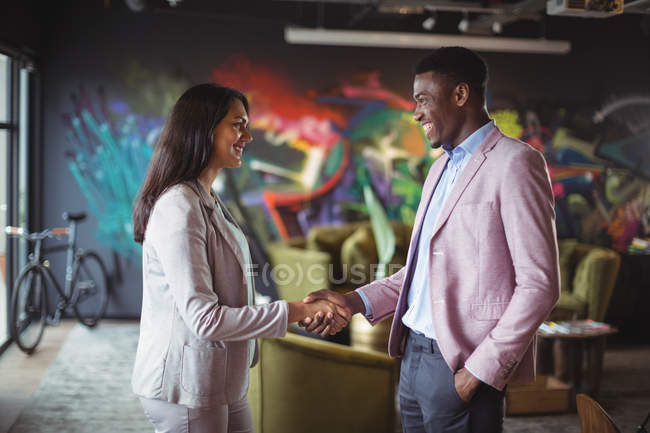 Businessman and a colleague shaking hands in office — Stock Photo