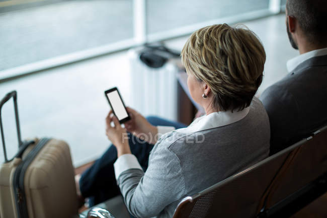 Geschäftsfrau benutzt Handy im Wartebereich am Flughafen-Terminal — Stockfoto