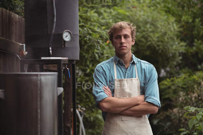 Портрет впевненого чоловіка в фартусі, що стоїть на домашній пивоварні — стокове фото